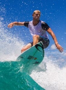 Surfer catching a wave at one of the stunning Bali Surfing Spots, showcasing clear blue skies and pristine ocean waters.